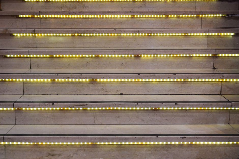 Sfeervolle LED-verlichting langs houten trapleuning.